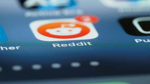 Close-up of a smartphone screen showing the Reddit app icon with a red notification bubble displaying the number 4. The app icon features Reddit's white alien logo on an orange background.