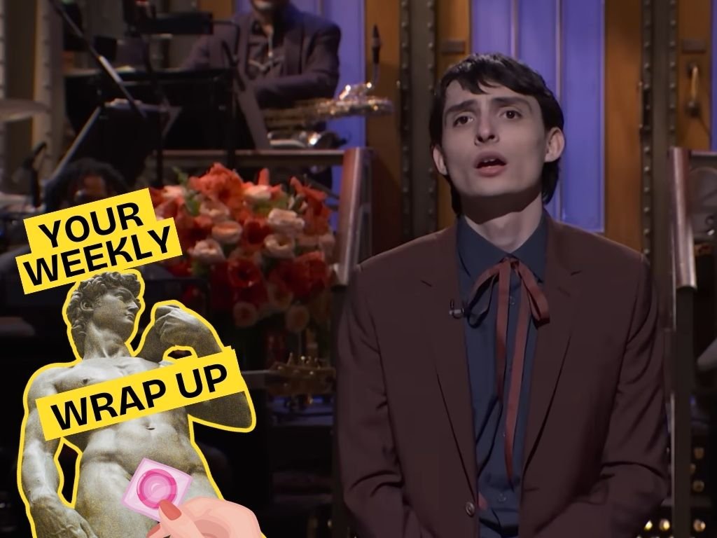 A person in a brown suit (Finn Wolfhard) sits on a TV studio stage with a live band blurred in the background. Overlaid on the left is a yellow-and-black graphic reading “YOUR WEEKLY WRAP UP,” alongside a cut-out statue and an illustrated hand holding a pink condom.