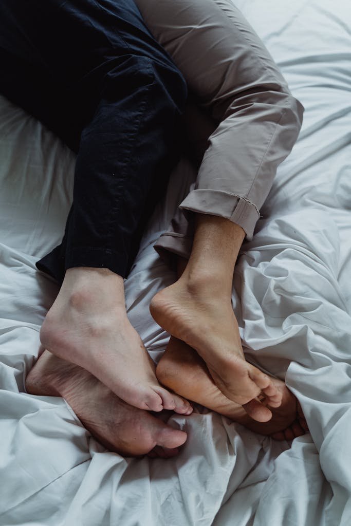 Close-up of a couple's feet entwined on a bed, expressing love and togetherness.