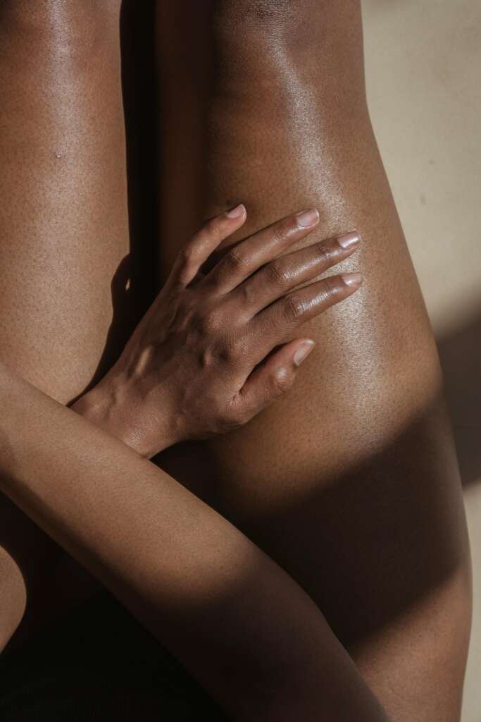 Crop naked black woman touching hip.