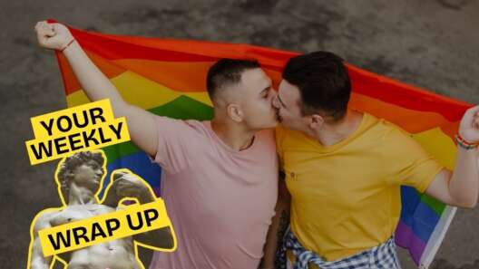 Two men kiss while holding a rainbow Pride flag behind them. A “Your Weekly Wrap Up” graphic featuring a classical statue and a condom illustration appears in the bottom left corner.